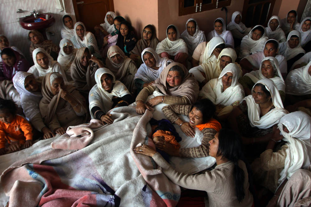 women mourn near the dead bodies of children who died in a road accident, at their home in a village