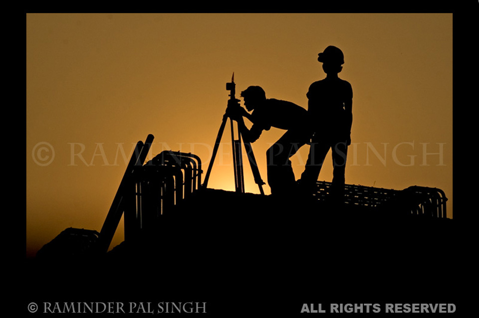 workers silhouetted against evening sky as they work on building an elevated road