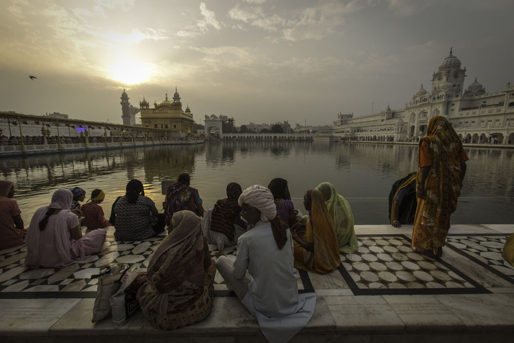 Devotees sit near sarowar sacred pond of Golden Temple