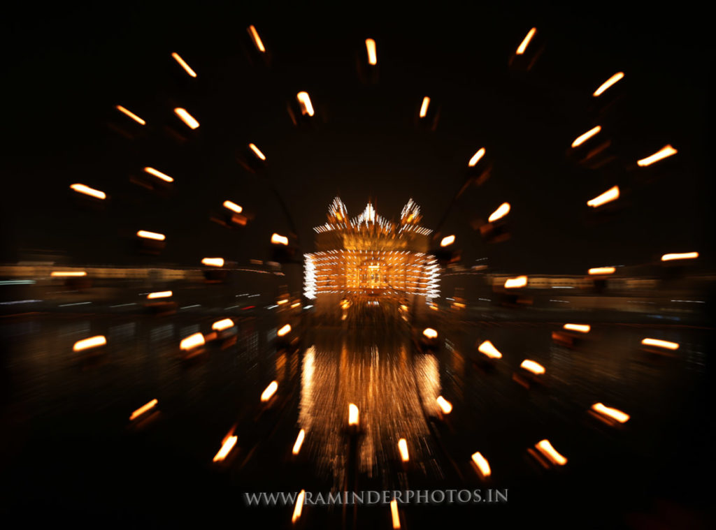 A zoom burst photo of lamp stand at illuminated Golden Temple at night Amritsar
