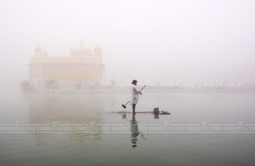 Golden Temple daily life winter fog sewadar on raft in Amritsar