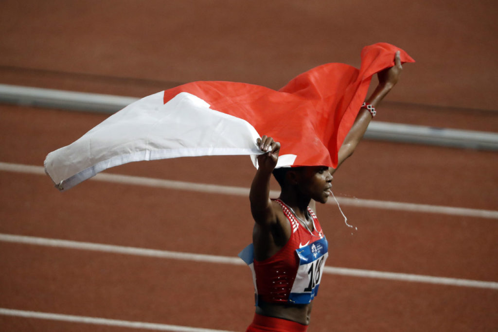 candid reaction of athlete holding flag as she spits after winning 3000m Steeplechase event