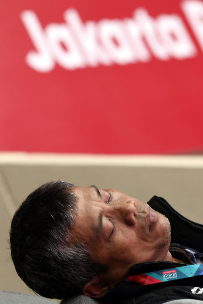 a man takes a break nap between Taekwondo matches at the Asian Games 2018 in Jakarta