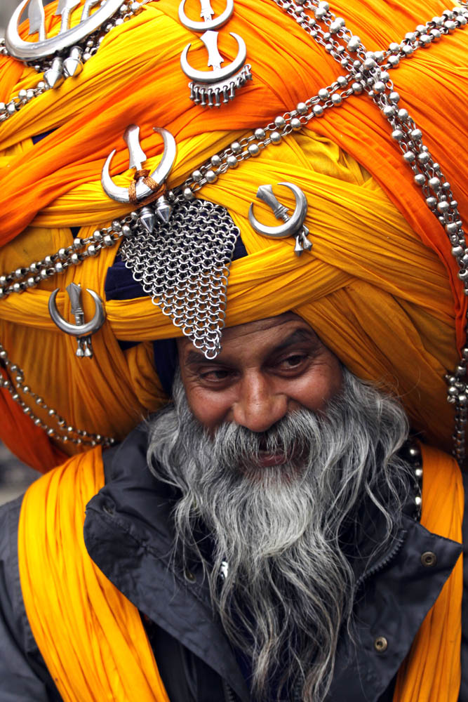 An Indian Sikh man Avtar Singh, a 'Nihang', who belongs to ancient Sikh warrior clan, supporting an over-sized turban walks in a street in Amritsar, India 30 January 2013. According to Avtar Singh, he wanders around spreading the message of Sikhism and to encourage youth of Punjab to stay away from drugs and become true Sikhs.