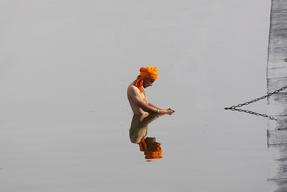 Sikh an takes holy dip in sarowar or sarcred pond of Darbar Sahib Tarn Taran Sikh temple shrine