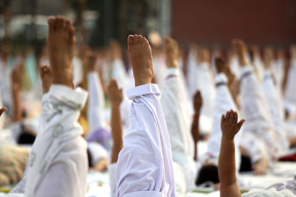 people perform yoga on yoga day as they raise their legs in air