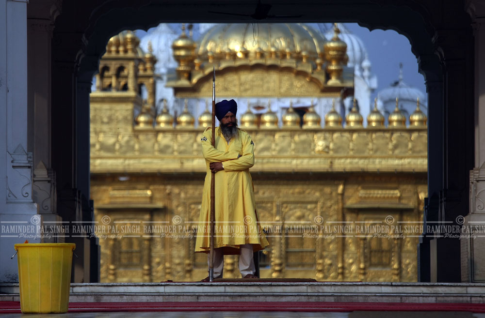 A Sikh guard called 'Sewadar' stands holding a spear at one of the entrances to the Golden Temple (seen in the backdrop), the holiest of Sikh shrines in Amritsar