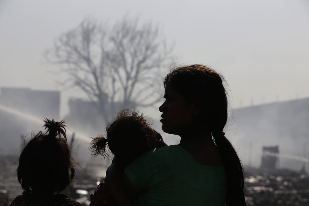 Silhouette image of a family as they watch their burnt house in a slum fire