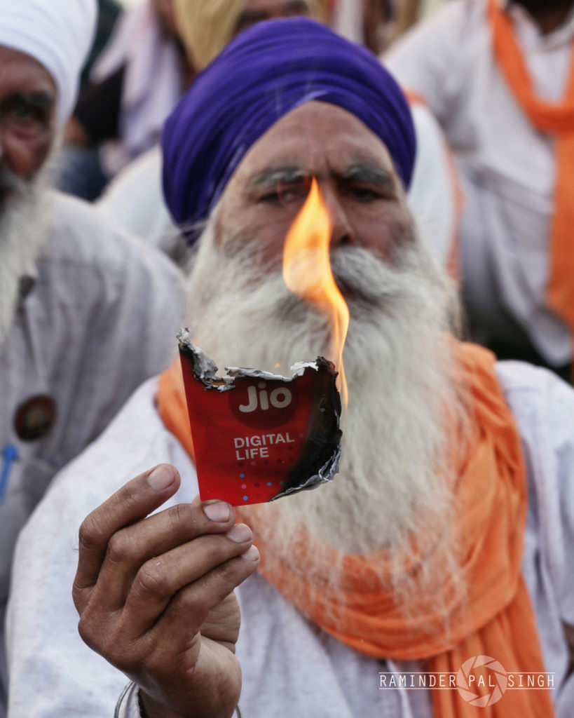 A farmer burns a pack of Jio Sim of Reliance Industries as a mark of protest