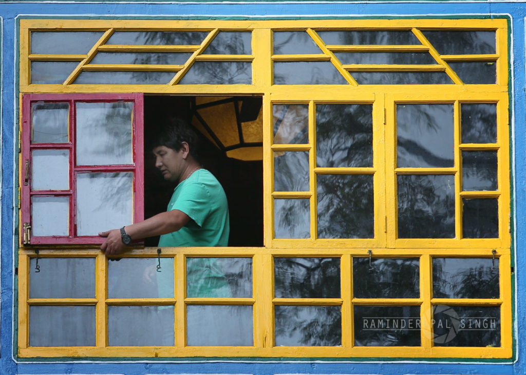 Man closes a beautiful colored window which is seen through frames of windows within a frame creating a beautiful composition