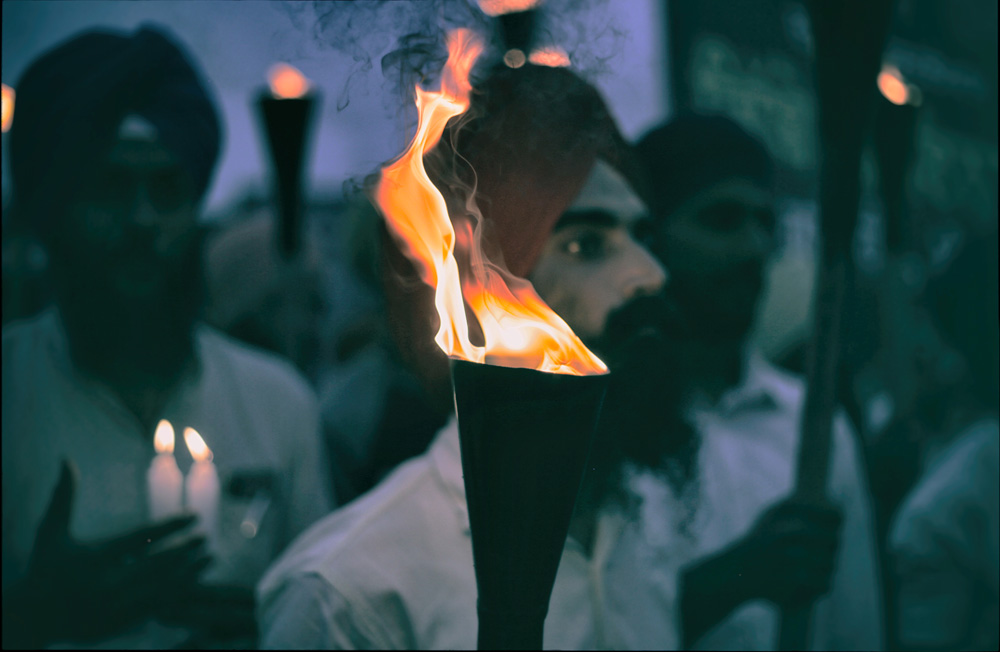 Sikh man holds a torch as he takes part in a demonstration