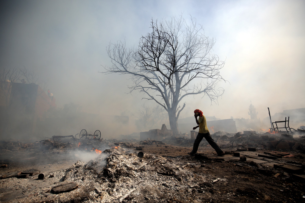 A man walks in a slum area that was burnt by a fire.