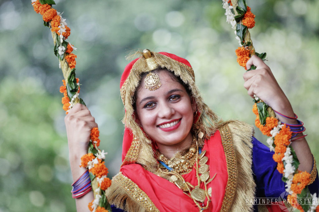 A Punjabi girl wearing traditional Punjabi attire takes rides on a swing as she celebrates Teej festival or Teeyan da teyohar in Amritsar Punjab