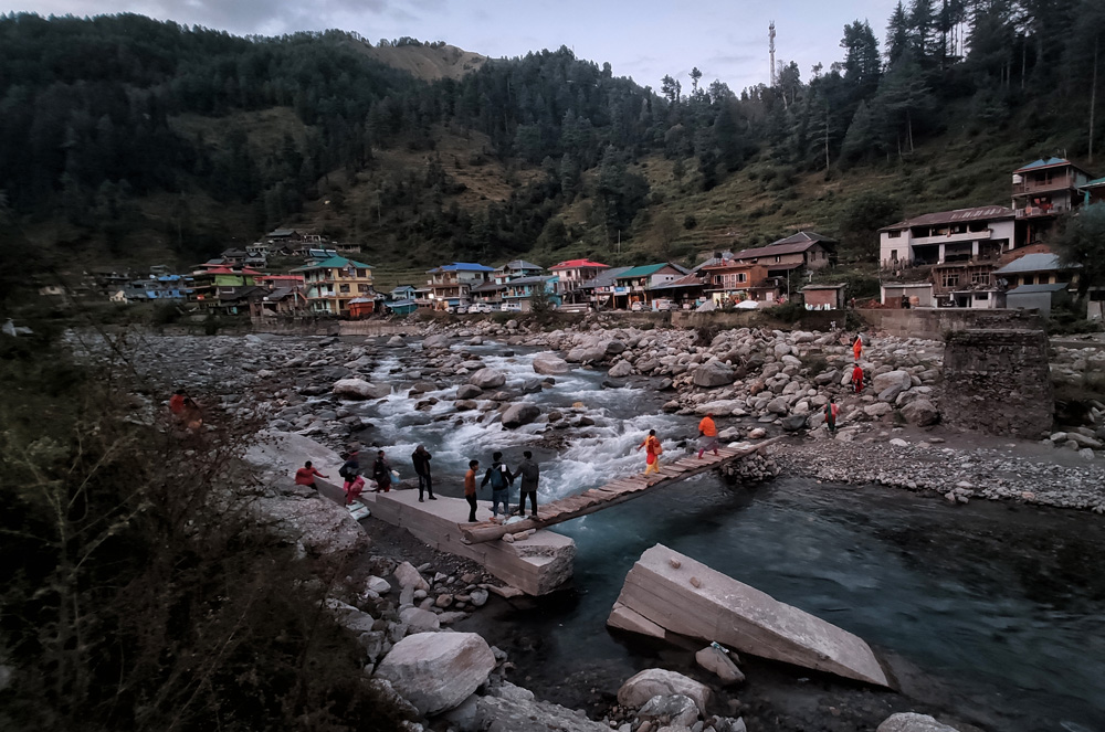 People cross a temporary wooden bridge over Uhl river in Barot